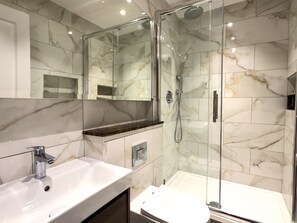 Une salle de bain moderne avec une douche à parois de verre, un lavabo blanc et des toilettes.