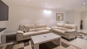 Un salon moderne avec un canapé d’angle beige, une table basse blanche et un tapis à motifs.