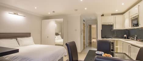 Une chambre d’hôtel équipée d’un lit, d’un bureau, d’une chaise et d’une petite kitchenette.