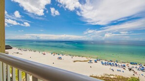 A beach with clear turquoise waters and a white sandy shore. There are several umbrellas and lounge chairs on the beach. - Grand Panama 809 Beachfront Escape, Beach Service + Pets OK! (Panama City Beach)