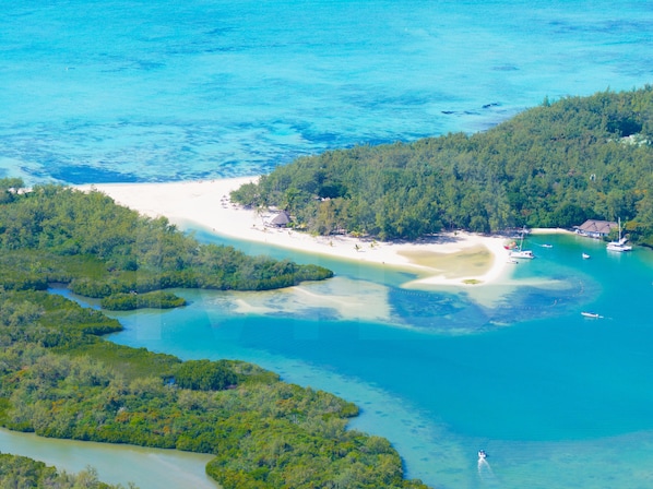 Eine Vogelperspektive einer tropischen Insel mit Strand, klarem Wasser und dichtem Wald.