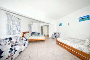 Une chambre avec deux lits, un canapé et une fenêtre avec des rideaux.