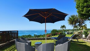 A patio with wicker furniture, a large umbrella, and a view of the ocean. - The Bay Villa 10 minutes by boat from Ile aux Cerfs (trou d'eau douce)