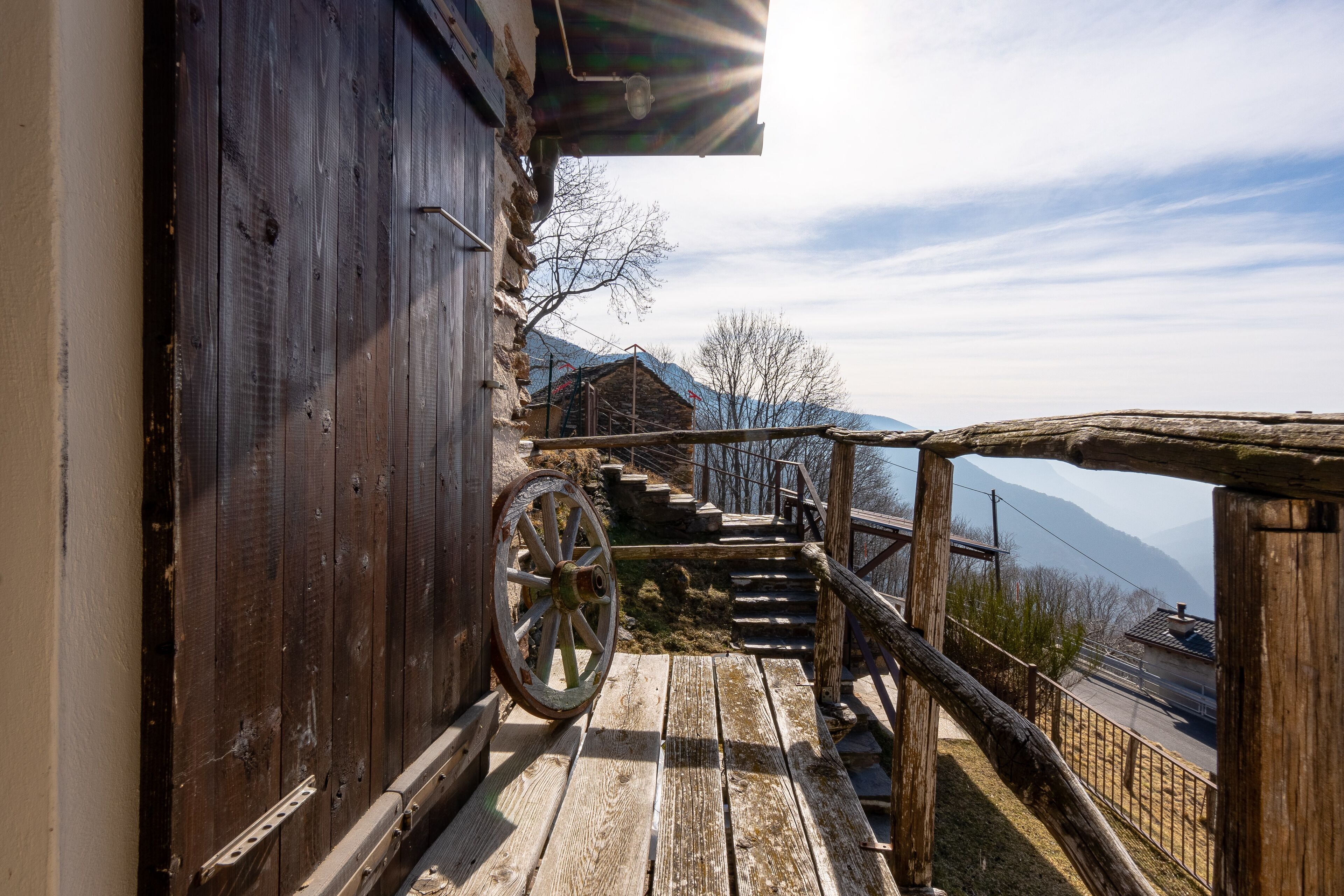 Una escalera de madera que conduce a una cabaña de montaña con una rueda en la parte superior.
