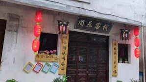 A building facade with a traditional Chinese architectural style, featuring a wooden door with intricate carvings and a signboard above it. - Tongle Inn (Wuyuan)