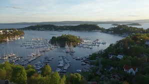 A marina with numerous boats docked, surrounded by greenery and residential buildings. - Tjuvholmen II As Home (Oslo)