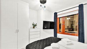 A hotel room with a bed, a TV, a wardrobe, and a window with curtains. - Tjuvholmen II As Home (Oslo)
