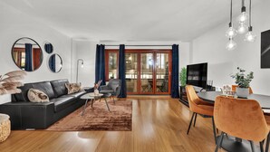 A modern living room with a black leather sofa, a round coffee table, and a dining area with a table and chairs. - Tjuvholmen II As Home (Oslo)