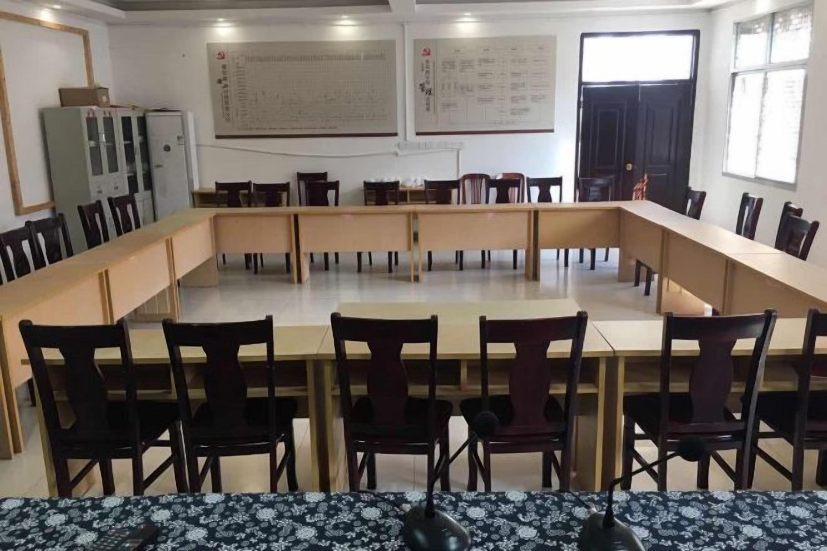 A conference room with a long table and chairs, whiteboard, and windows.