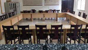 A conference room with a long table and chairs, whiteboard, and posters on the walls. - Youjian Nanshan Hotel (Xinchang)