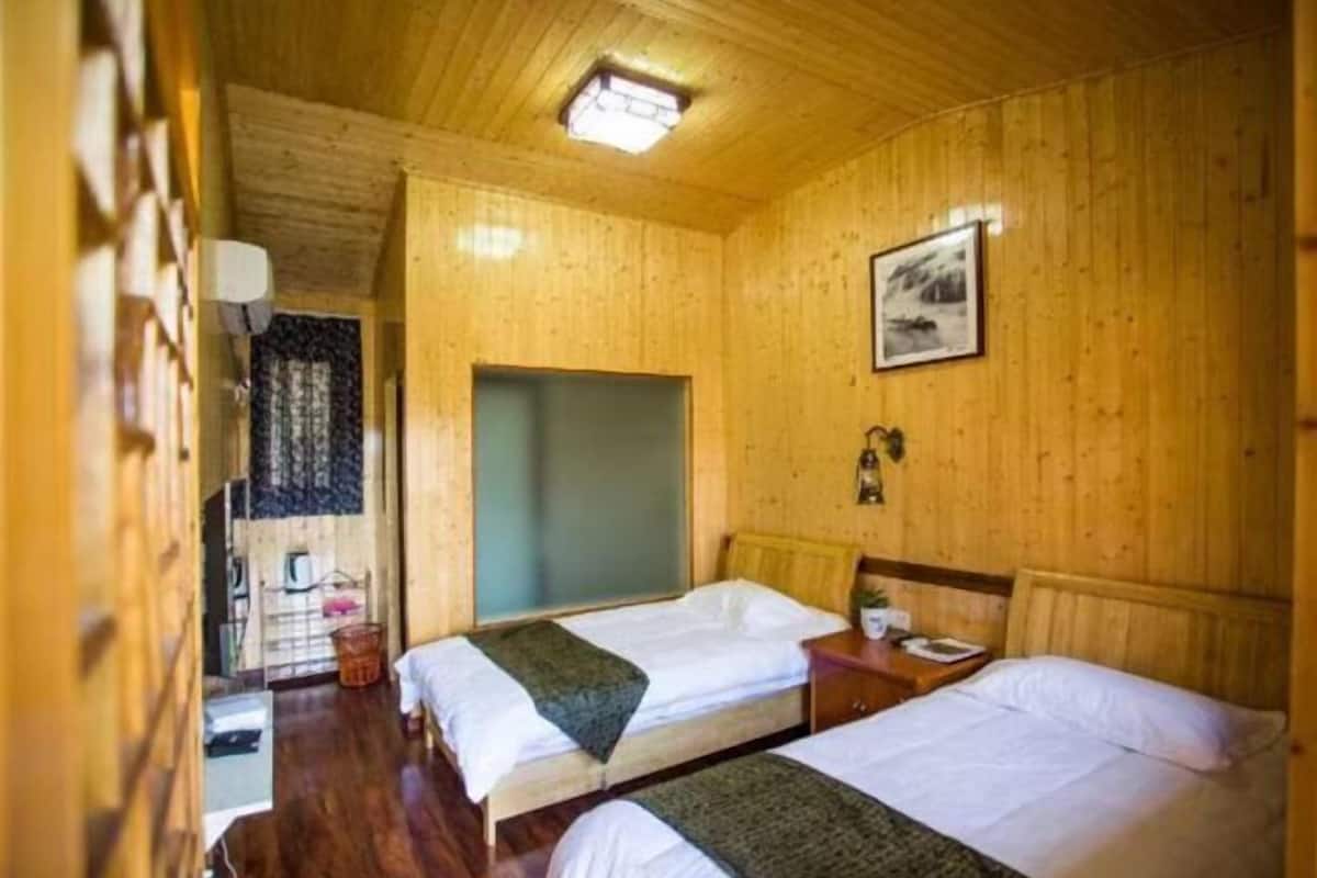 A wooden room with two beds, a window, and a door.