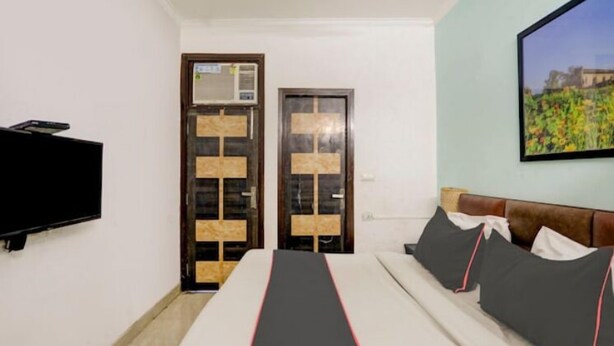 A room with a bed, a TV, and two doors. - Victoria Palace (New Delhi)