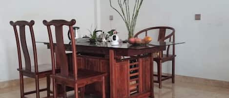 A wooden dining table with four chairs, a potted plant, and a fruit bowl.
