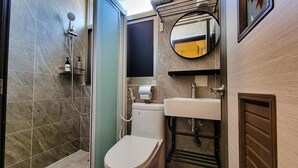 Un baño pequeño con ducha, inodoro y lavamanos.