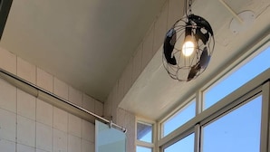 Un baño moderno con ducha de vidrio, tocador con espejo y un amplio ventanal con vistas a la ciudad.