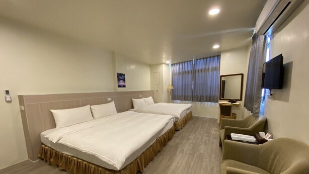 Habitación de hotel con dos camas, un escritorio, una silla, un televisor y un aire acondicionado.