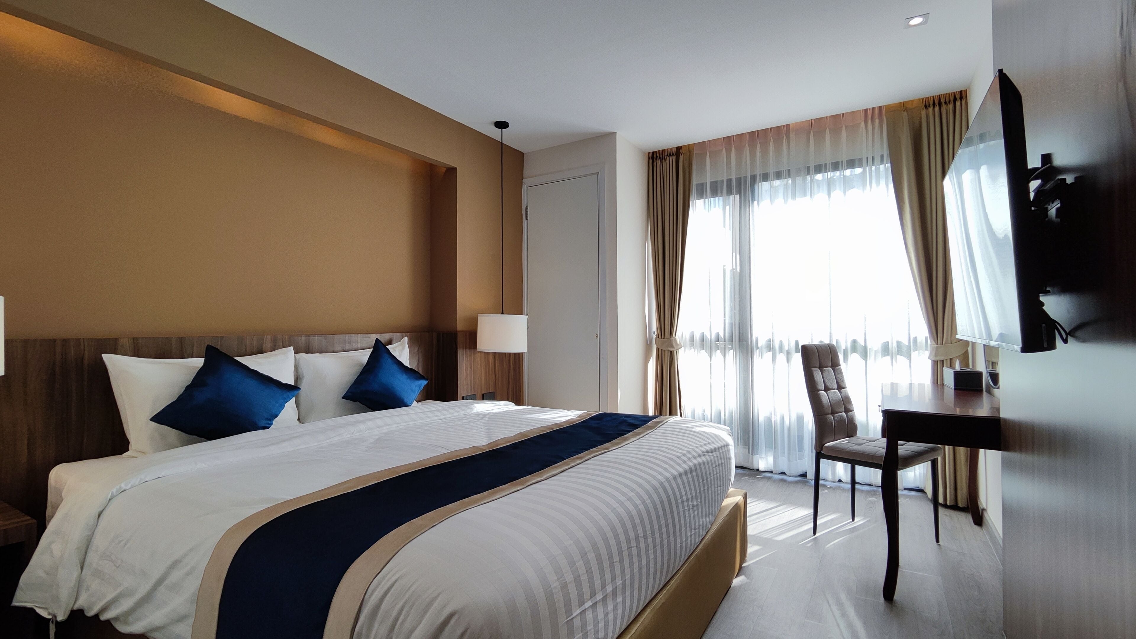 A hotel room with a large bed, a desk, and a chair.