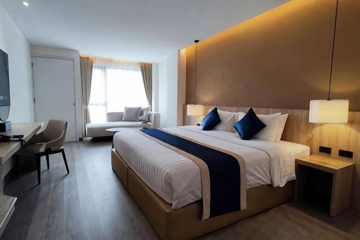 A hotel room with a large bed, bedside tables, a desk, and a chair.