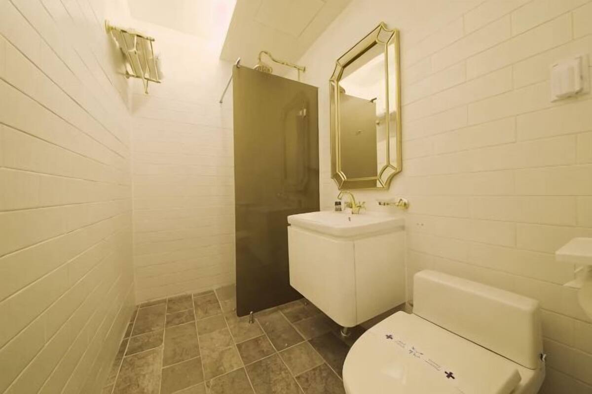 Un bagno con pareti piastrellate di bianco, un lavandino bianco, un water e una porta doccia.