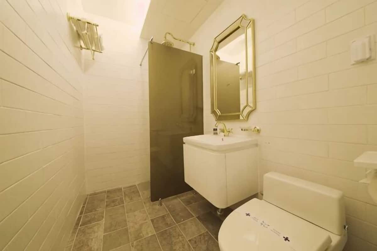 A bathroom with white tiled walls, a white sink, a toilet, and a shower door.
