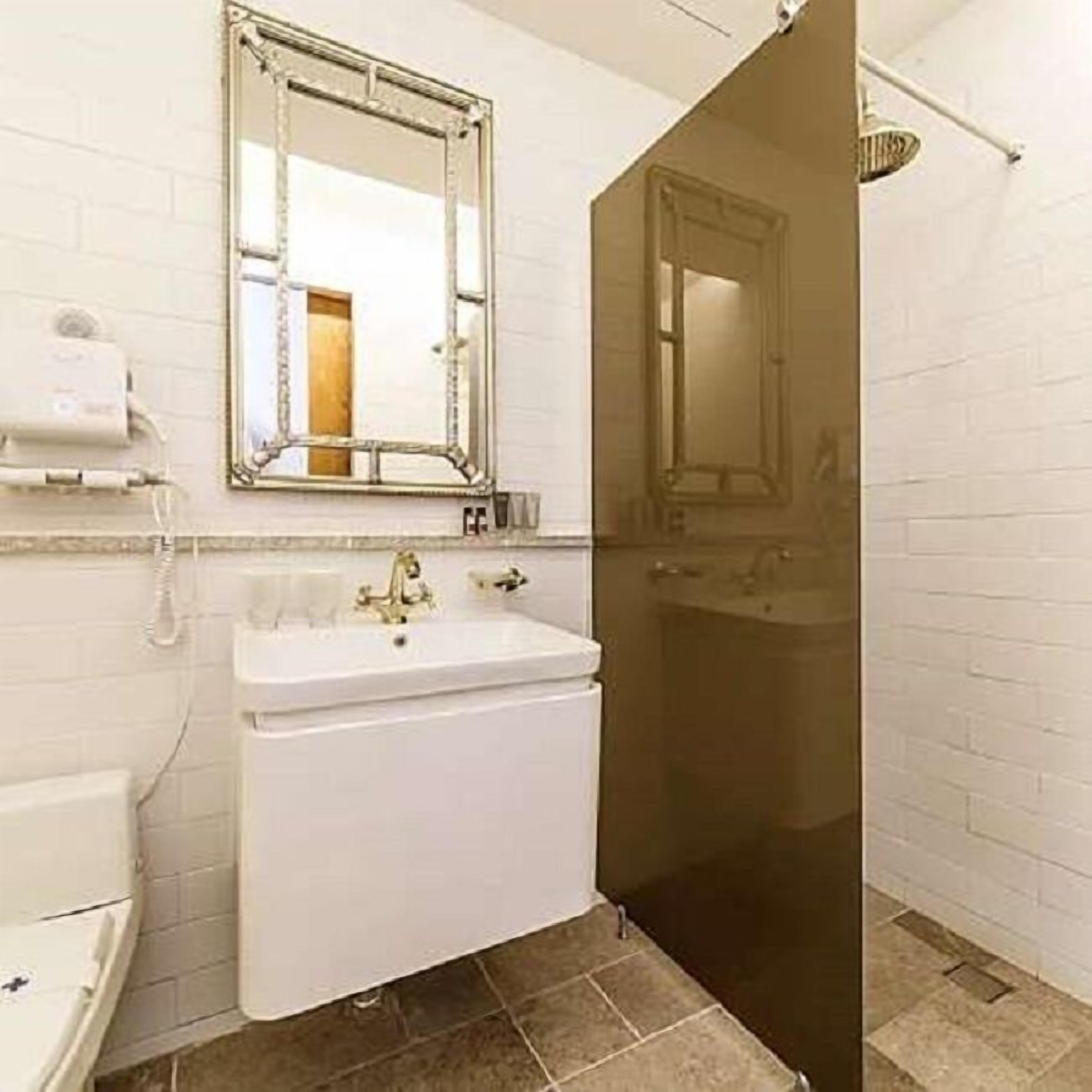 A bathroom with a white sink, a mirror, and a shower.