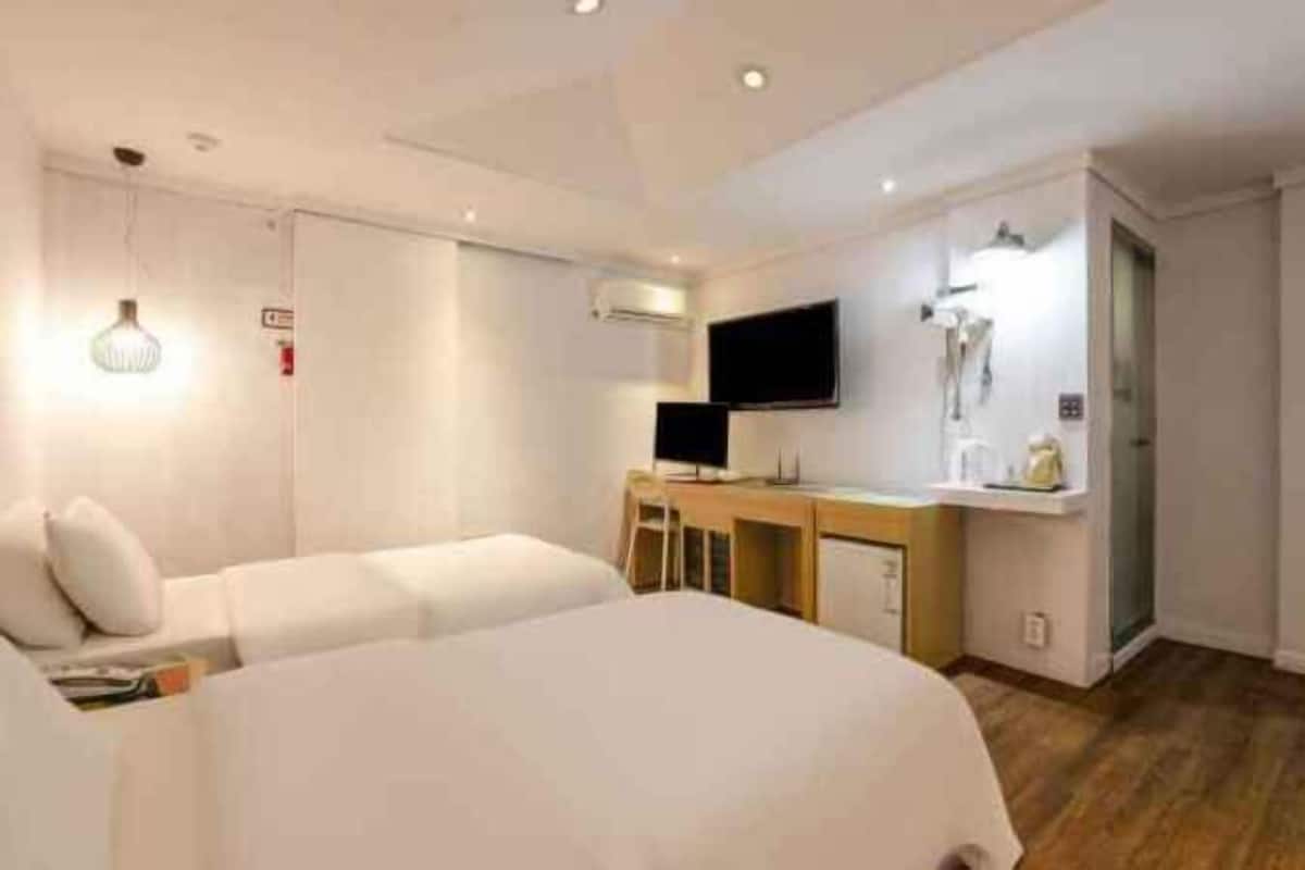 Una camera d'albergo con un letto, una scrivania, una sedia, una televisione e una lampada.