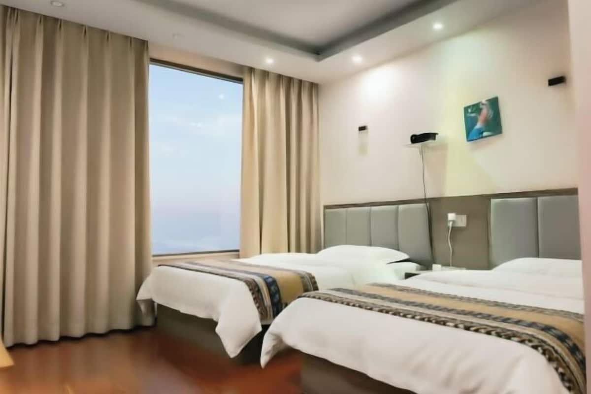 Habitació d'hotel amb dos llits, un finestral gran i vista al cel.