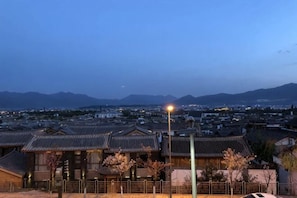 A traditional Japanese building with a tiled roof, surrounded by a fence, and a street lamp in the foreground. - Lijiang cloud color · July time Inn (Lijiang)