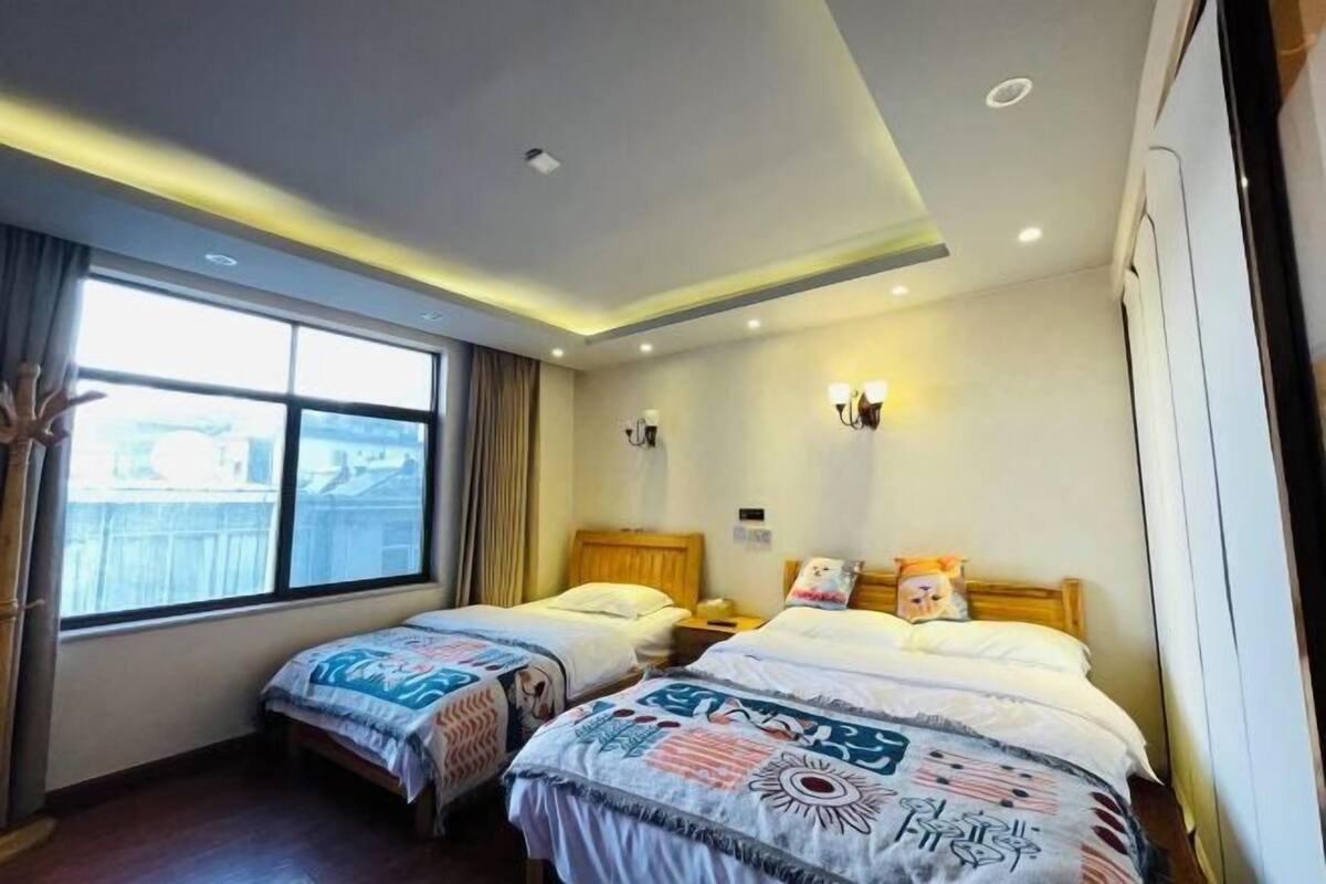 Habitació d'hotel amb dos llits, una finestra gran i un sostre amb il·luminació empotrada.