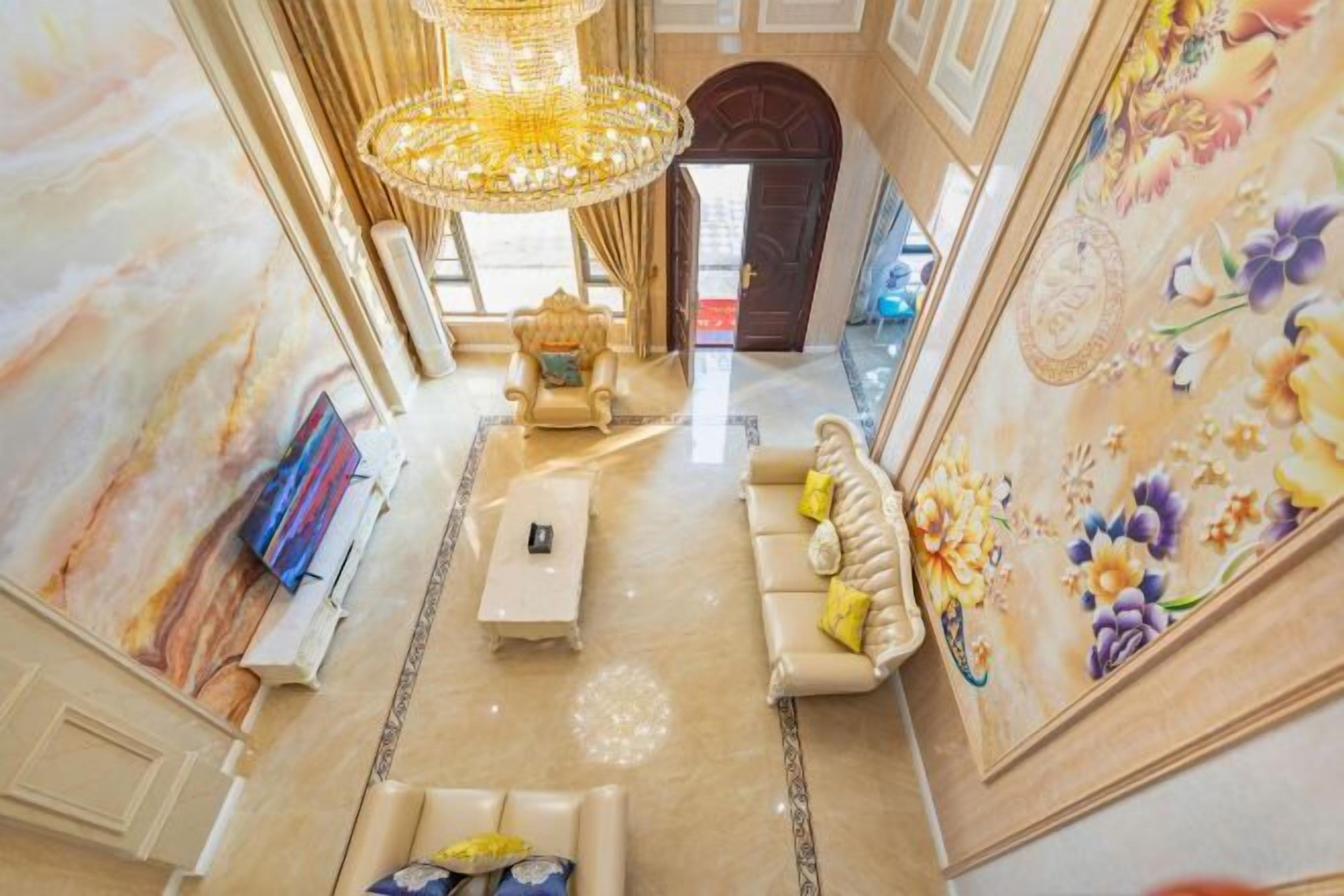 Un intérieur luxueux agrémenté d’un lustre, de fauteuils confortables et d’une fresque murale aux motifs floraux.