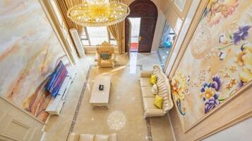 Un intérieur luxueux agrémenté d’un lustre, de fauteuils confortables et d’une fresque murale aux motifs floraux.