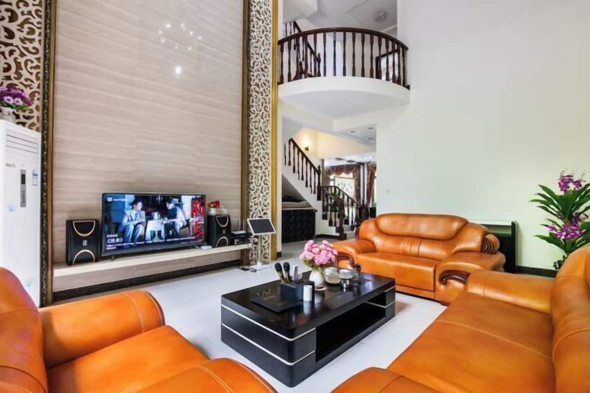 Uma sala de estar moderna com sofás de couro, uma TV de tela plana e uma escada que leva a um andar superior.