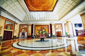 A spacious lobby with a central fountain, a large floral mural, and a high ceiling with a circular design.