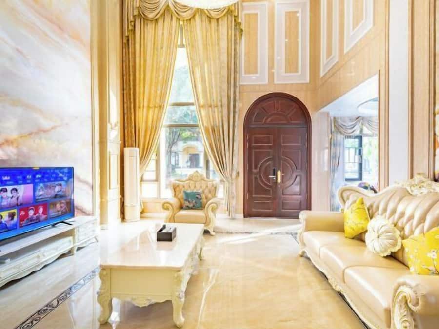 A luxurious living room with a television, a sofa, a coffee table, and a large arched doorway.
