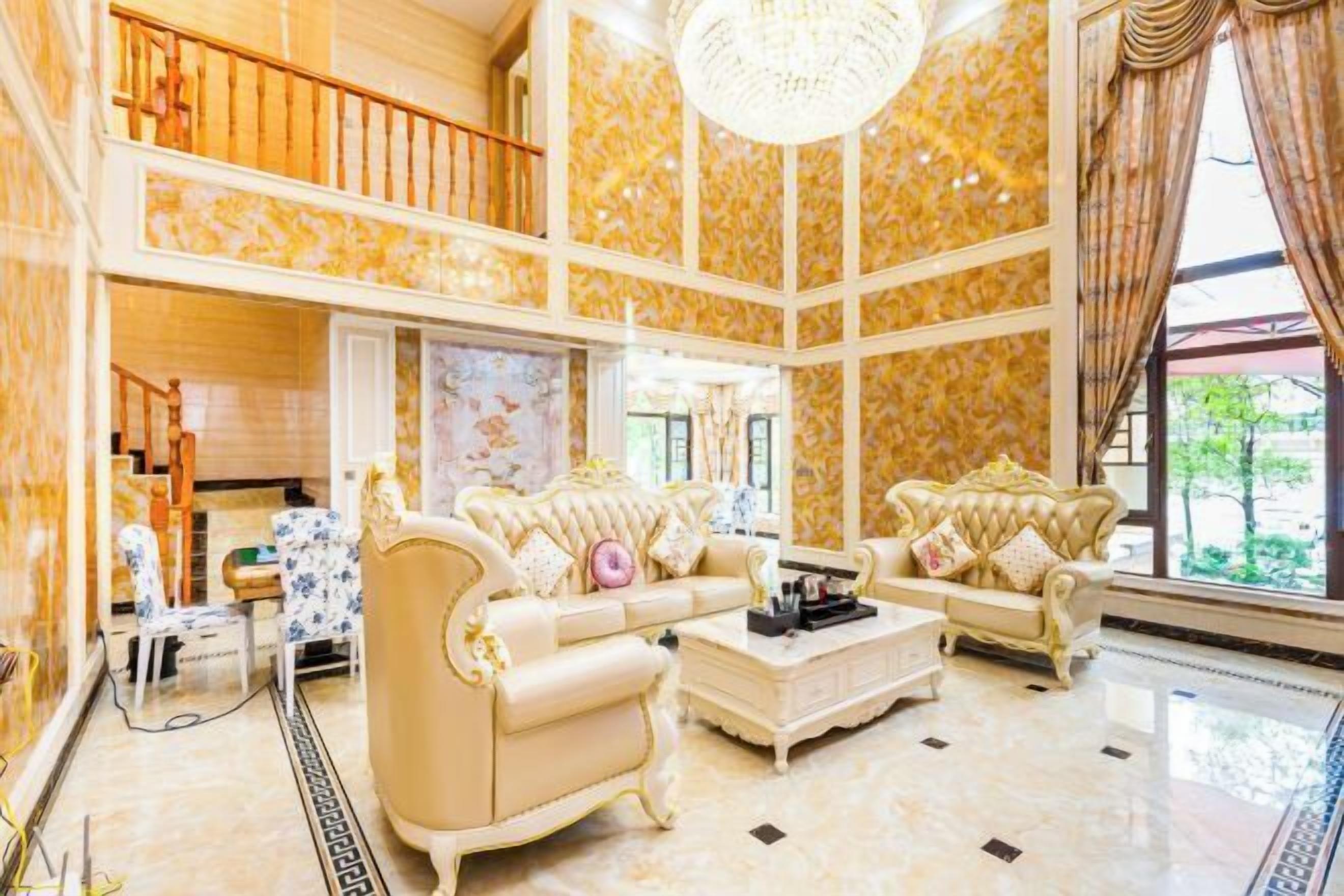 A spacious living room with a high ceiling, two sofas, a coffee table, and a chandelier.