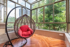 A room with a hanging chair, large windows, and a wooden floor. - Qingyuan Hengda Yilin Yashe Drifting Holiday Villa (Qingyuan)