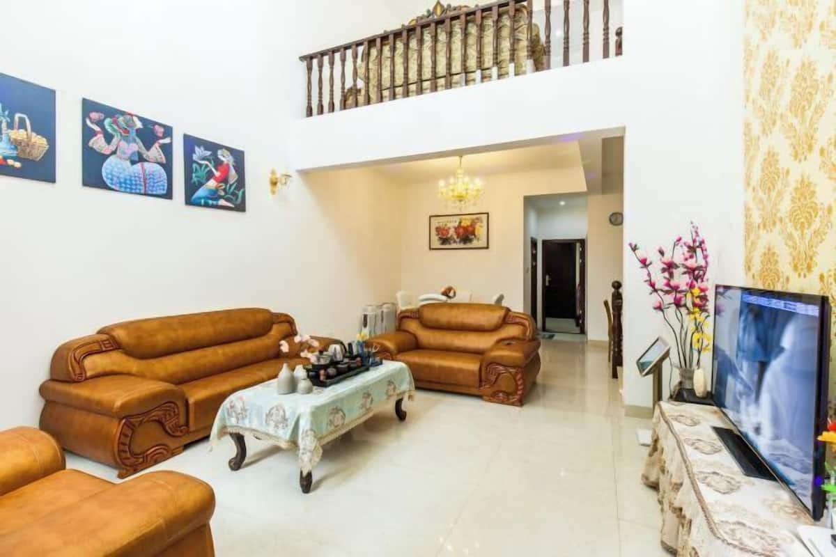 Uma sala de estar com dois sofás, uma mesa de centro, uma TV e obras de arte nas paredes.
