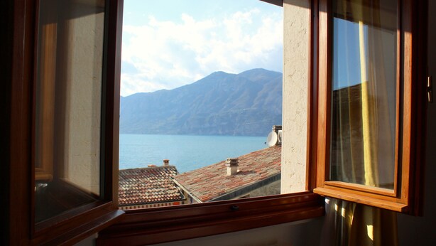 A window with a view of a mountain and a body of water. - Gaspar House (Brenzone sul Garda)