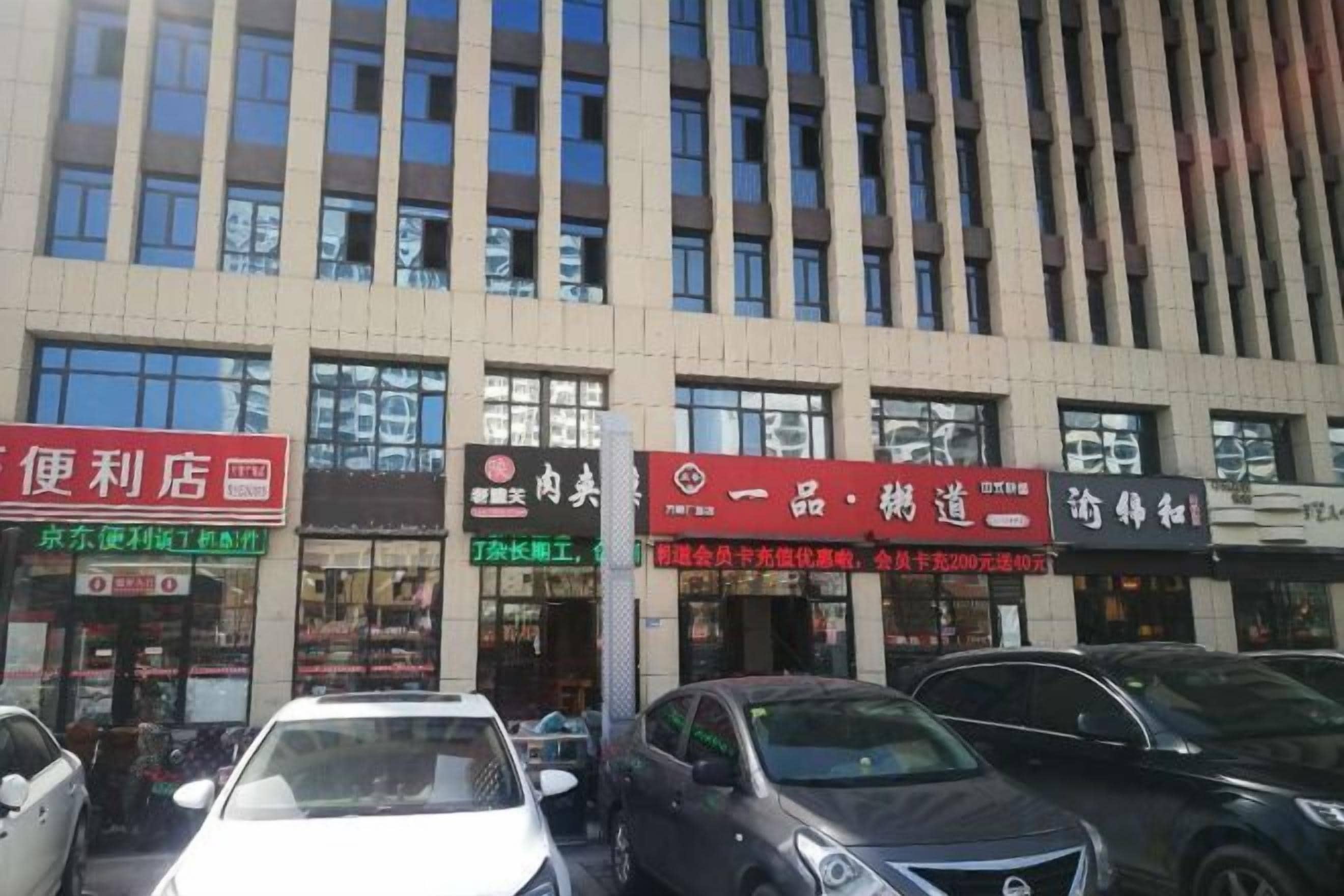 Un edificio de varios pisos con varias tiendas, incluyendo una tienda de conveniencia y una farmacia.
