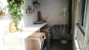 Een wasserette met een wasmachine, droger en een droogrek.