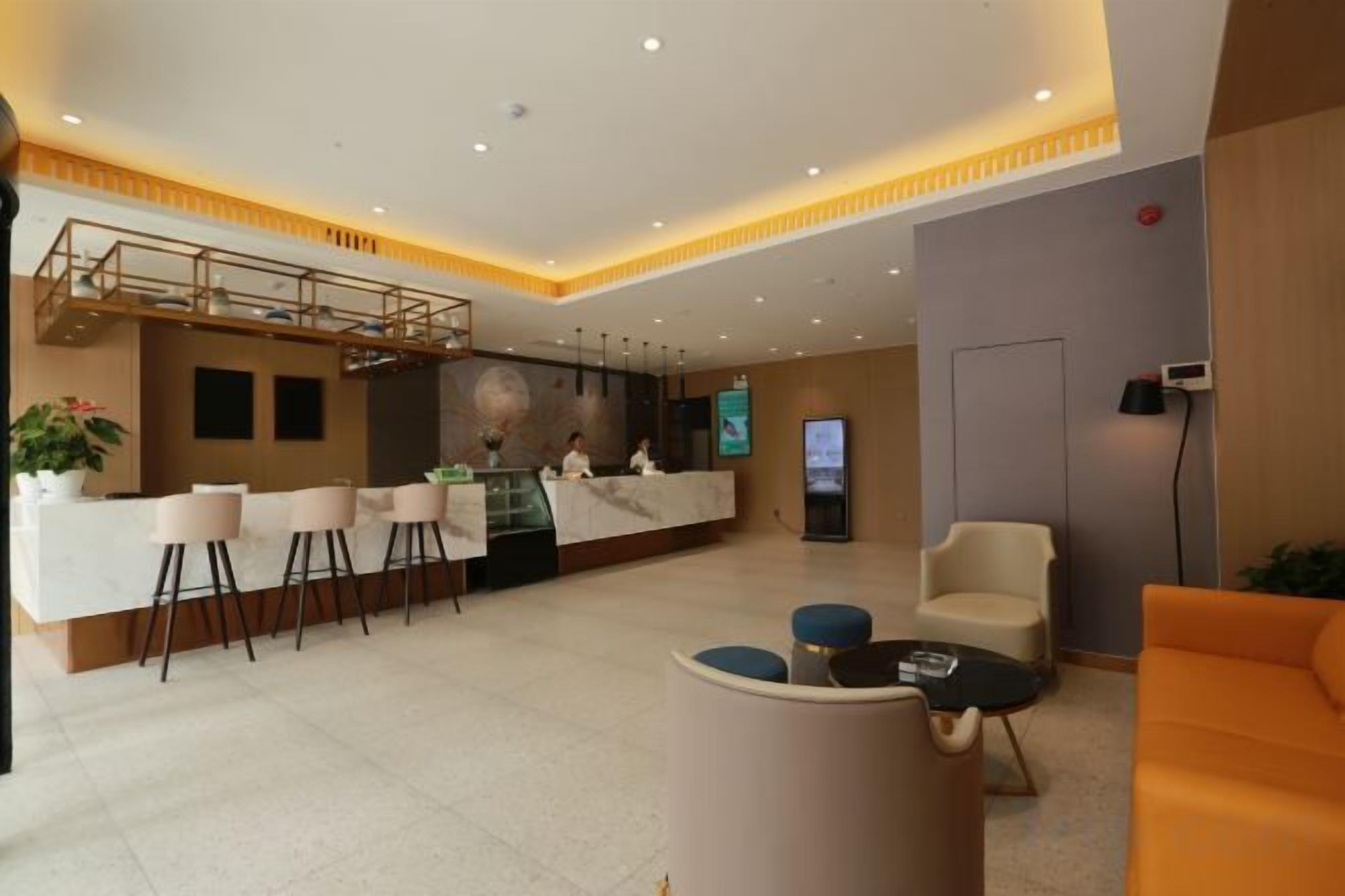 En hotellobby med en receptionsdisk, en sittgrupp och en trappa.