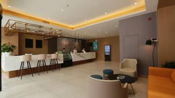 En hotellobby med en receptionsdisk, en sittgrupp och en trappa.
