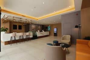 Un hall de hotel con mostrador de recepción, zona de estar y una escalera.