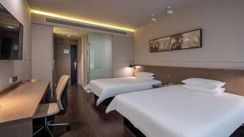 Een hotelkamer met twee bedden, een bureau en een stoel.
