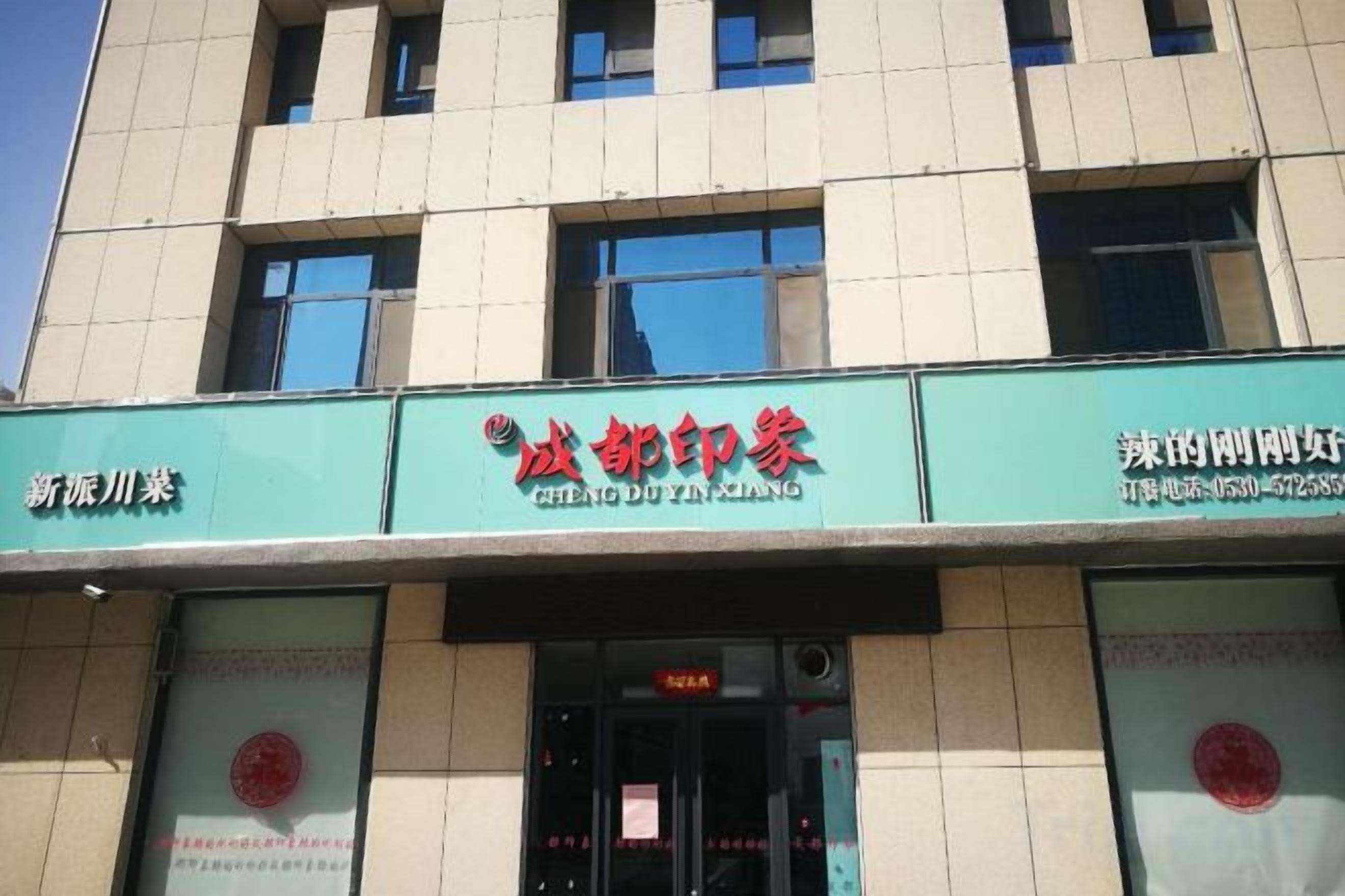 En byggnad med ett grönt solskydd som visar namnet ”CHENGDU ZHENG” och ett rött sigill.