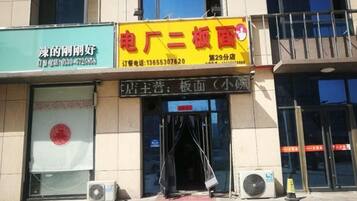 A building with a storefront featuring a yellow sign with red and black text.