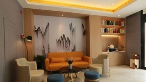 Een moderne lobby met een bank, twee fauteuils, een salontafel en een boekenkast.