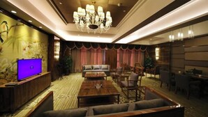 Een ruime hotel lobby met een grote kroonluchter, een televisie, een bank en een eetgedeelte.