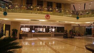 A spacious lobby with a reception desk, a glass balustrade, and a decorative circular emblem.