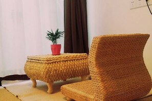 A wicker chair and ottoman in a room with a potted plant on the ottoman. - Tongli Jizhu Inn (Suzhou)